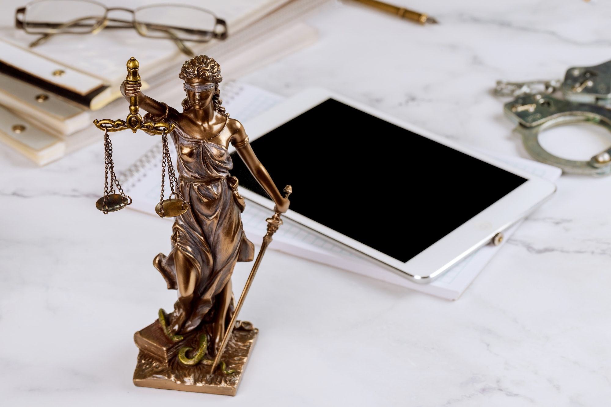Lawyer Statue of Justice with scales lawyers symbols office working on a digital tablet