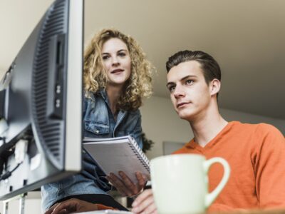 Two colleagues at desk looking at computer monitor