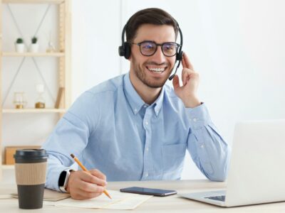 Smiling customer support service operator with hands-free headset working in office